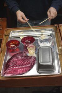 Playing objects on a metal pan with bamboo skewers.